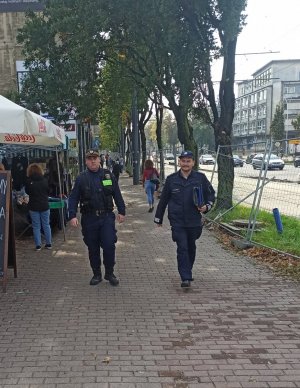 Policjant i strażnik miejski idą ulicami miasta