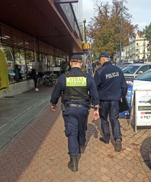 Policjant i strażnik miejski patrolują ulicę