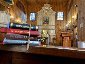na pierwszym planie leżą książki w języku polskim, w tle ołtarz kościoła