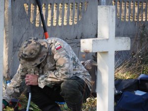 policyjny związkowiec przycina rośliny na cmentarzu w Kisielinie