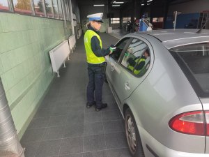 policjantka daje kierowcy opaskę odblaskową przez uchyloną szybę w samochodzie