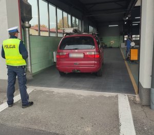 policjant patrzy na samochód, który wjechał do stacji diagnostycznej