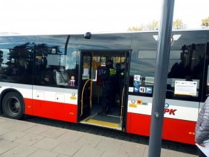 autobus stoi na przystanku - widać w środku pasażerów i 2 funkcjonariuszy straży miejskiej podczas kontroli