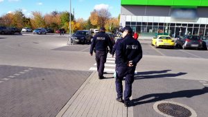 policjanci idą po parkingu sklepowym
