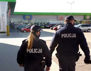 policjanci idą po parkingu sklepowym