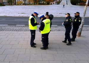 policjanci na przystanku rozmawiają z kobietą, obok stoi patrol straży miejskiej