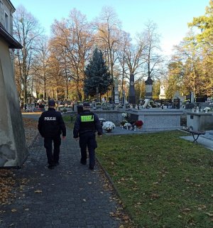 Policjant i straznik miejski patroluja rejon cmenatrza