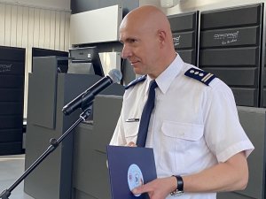 inspektor Dariusz Atłasik komendant Miejski Policji w Częstochowie składa życzenia cywilom, którzy siedzą przy stole w auli Komendy. Komendant stoi przy mikrofonie.