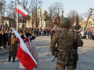 na pierwszym planie żołnierz stojący przy pomniku Józefa Piłsudskiego