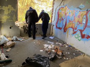 policjant i strażnik miejski sprawdzają pomieszczenie znajdujące się w opuszczonym budynku