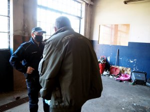 policjant rozmawia z mężczyzna w opuszczonym i zaniedbanym pomieszczeniu
