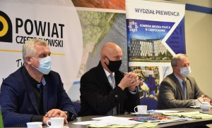 3 mężczyzn siedzi przy stole i prowadzą inaugurację kampanii