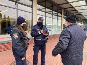 policjant i strażniczka miejska legitymują mężczyznę przed sklepem