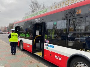 policjantka idzie wzdłuż stojącego na przystanku autobusu