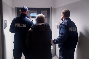 policjanci prowadzą zatrzymanego korytarzem w komisariacie