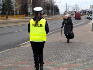 policjantka idzie po chodniku wzdłuż jezdni w kierunku starszej kobiety