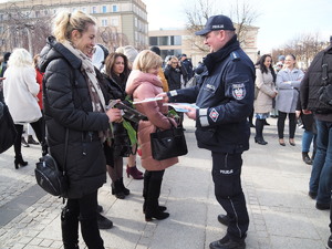 policjant wręcza poradnik stojącym na Placu Biegańskiego kobietom