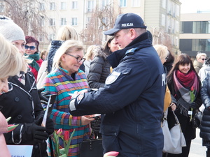 policjant wręcza poradnik stojącym na Placu Biegańskiego kobietom