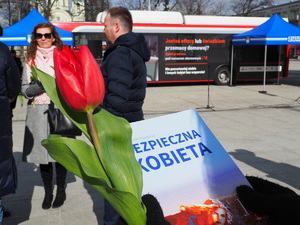 zbliżenie na poradnik dla kobiet i kwiatka, które4 trzyma kobieta stojąca na Placu Biegańskiego