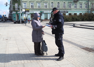 policjant wręcza kobiecie poradnik na Placu Biegańskiego