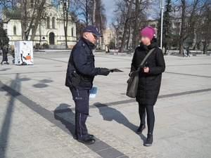 policjant wręcza kobiecie poradnik na Placu Biegańskiego