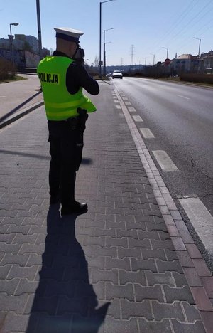 policjant Ruchu Drogowego podczas przeprowadzania czynności służbowych z użyciem urządzenia do pomiaru prędkości