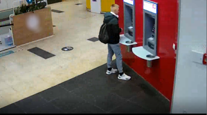 mężczyzna stoi przy bankomacie wewnątrz pomieszczenia