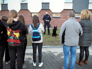 uczniowie stoją przed komenda i słuchają prelekcji w wykonaniu przewodnika psa służbowego i zespołu konnego