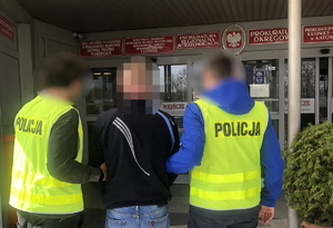 policjanci kamizelkach odblaskowych prowadzą zatrzymanego do prokuratury w Katowicach