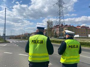 policjanci stoją tyłem do fotografującego, patrzą w kierunku przejścia dla pieszych