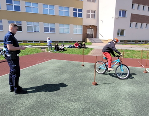 policjanci na miasteczku rowerowym oceniają jeżdżących na rowerze uczniów