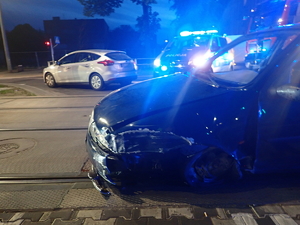 uszkodzony samochód marki Ford stoi na drodze przy torowisku tramwajowym, w tle radiowóz policyjny