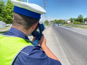 policjant z ręcznym miernikiem prędkości kontroluje prędkość nadjeżdżających samochodów