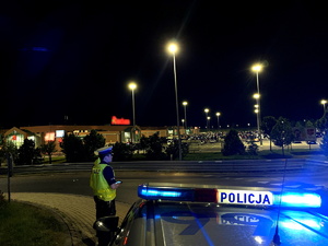 na pierwszym planie radiowóz, policjanci, w tle parking centrum handlowego