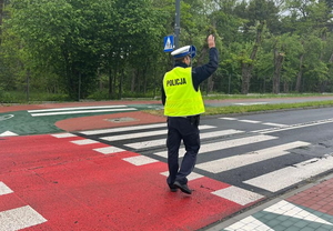 policjant z uniesioną ręką daje znak kierującemu do zatrzymania się