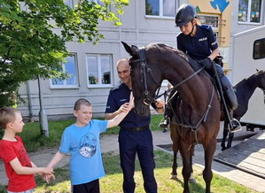 policjantka na koniu i policjant podczas spotkania z uczniami szkoły przed budynkiem