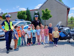 policjantka i policjant pozują do zdjęcia z grupą przedszkolaków