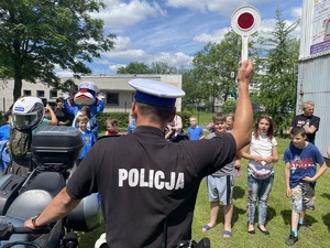 policjant pokazuje dzieciom tarczę do zatrzymywania pojazdów