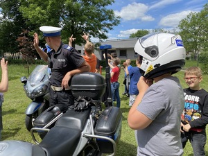 policjant stoi przy motocyklu, obok dziecko w kasku policyjnym