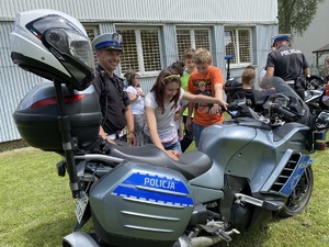 policjant stoi przy motocyklu, obok dziecko w kasku policyjnym