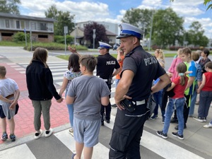 policjanci z uczniami uczą się przechodzić prawidłowo przez pasy