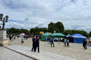 Policjanci w granatowych mundurach podczas zabezpieczenia pielgrzymki na błoniach jasnogórskich, w tle Jasna Góra i pielgrzymi