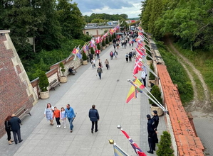 Policjanci w granatowych mundurach podczas zabezpieczenia pielgrzymki na błoniach jasnogórskich, w tle Jasna Góra i pielgrzymi