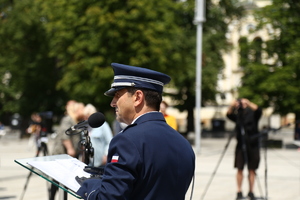 policjant stoi przed mównicą i przemawia do uczestników uroczystości