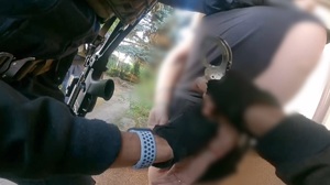 trzech policjantów oddziału kontrterrorystycznego zakłada kajdanki kobiecie na ręce trzymane z tyłu