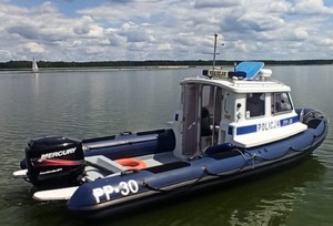 zdjęcie przedstawia policyjnej łodzi patrolowej, która zacumowana jest na zalewie wodnym Poraj