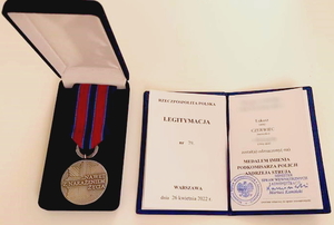 medal z napisem &quot;Nawet z narażeniem, życia&quot;, obok legitymacja należąca do wyróżnionego Łukasza Czerwca