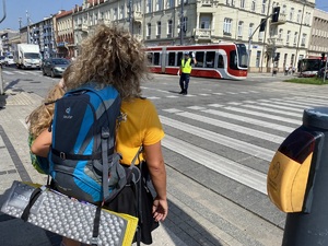 policjant na skrzyżowaniu kieruje ruchem, widać przechodzących przez przejście dla pieszych pielgrzymów