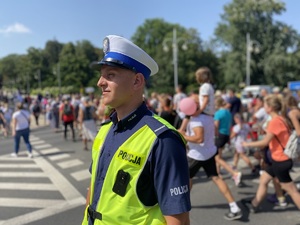 policjant na skrzyżowaniu kieruje ruchem, widać przechodzących przez przejście dla pieszych pielgrzymów