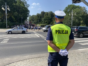 policjant stoi przed przejściem dla pieszych, w tle widać przejeżdżające samochody